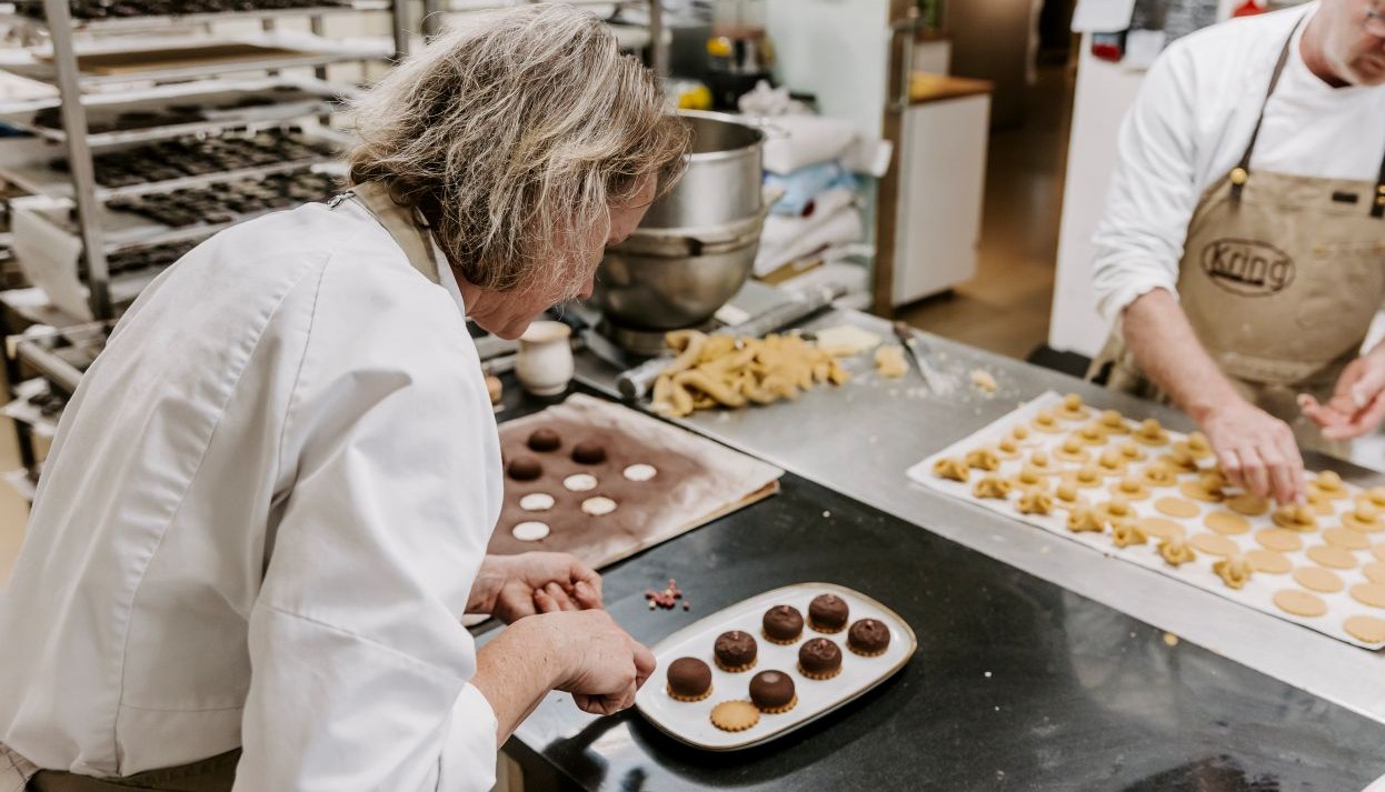 På billedet ses to konditorer der laver chokolade med marcipan indhold. Kring Chokolade laver håndlavet chokolade i deres værksted i butikken i Middelfart 