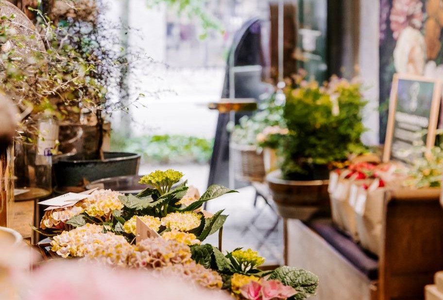 På Billedet ses indgangen til Jan Munch blomsterbutik. Gangen er fyld med forskellige planter og blomster. i forgrunden ses Hortensia i lyserøde nuancer 