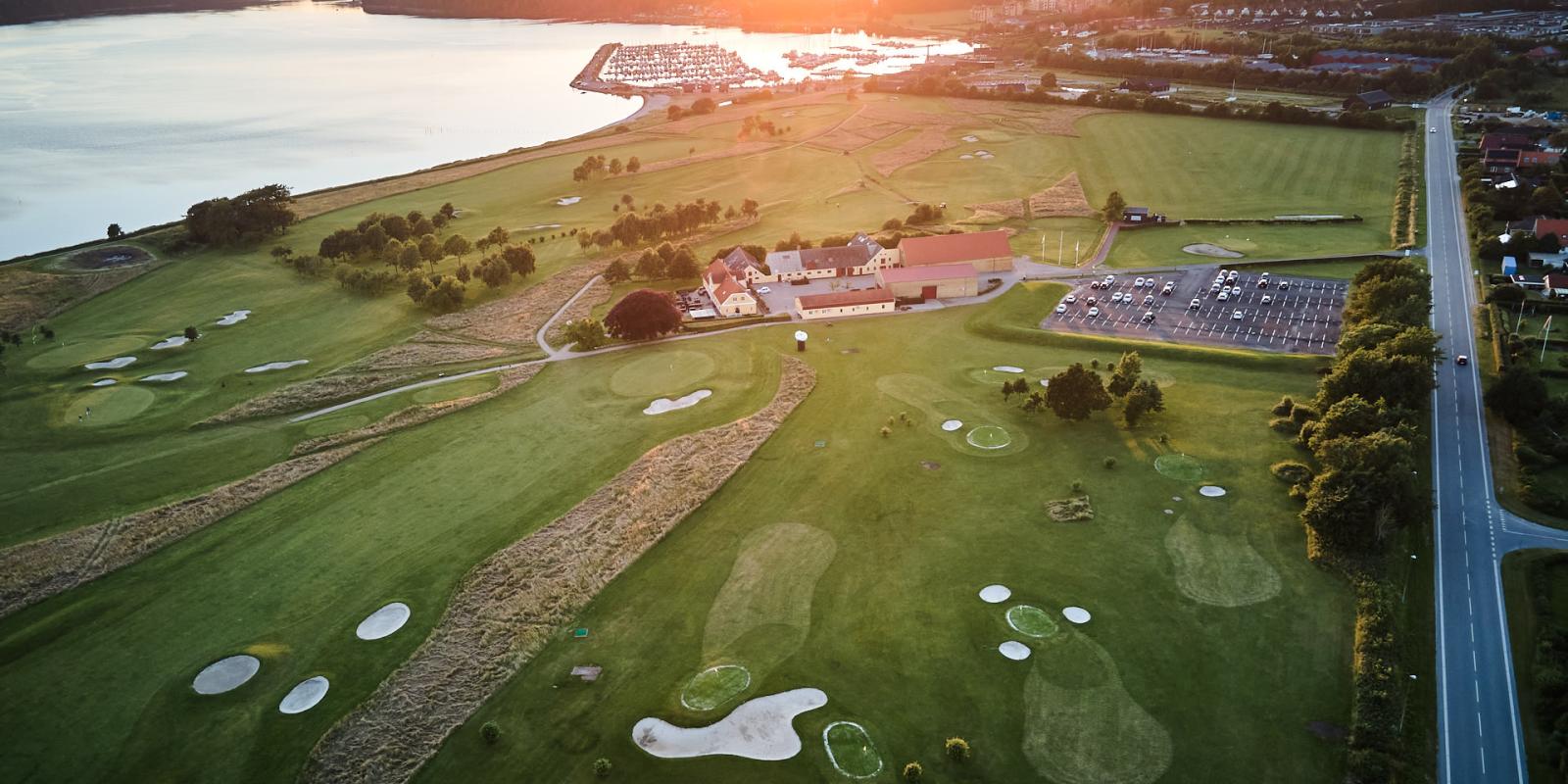 Dronebillede af golfbane i Middelfart. Man kan se Lillebælt i baggrunden. Solen er ved at gå ned 