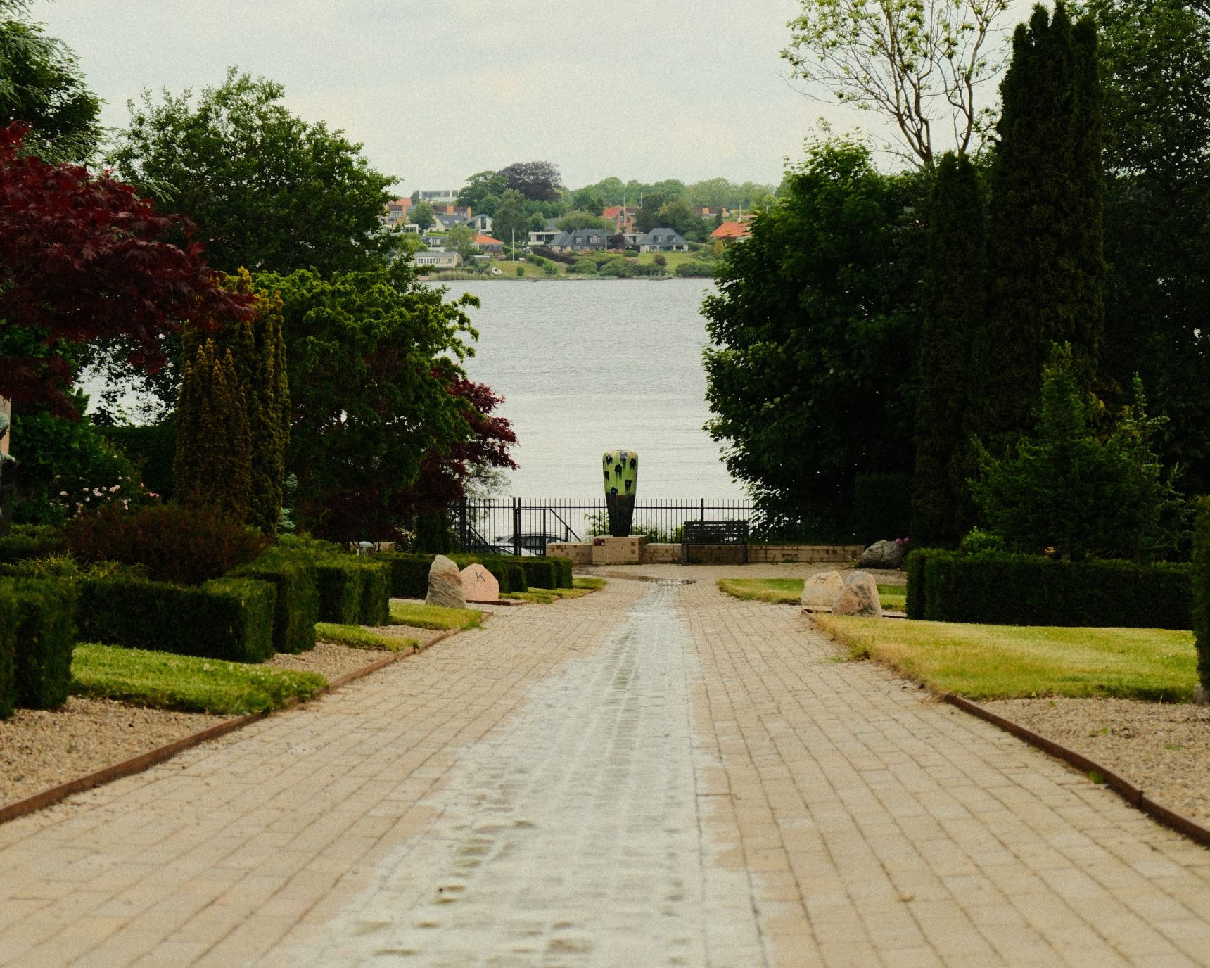 Kirkegården i Middelfart. For enden af en stil en belagt stil står en stor krukke. I midten af stien løber vandet fra regn ud i Lillebælt