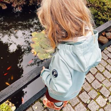 Pige der nysgerrigt kigger ned i en dam med fisk